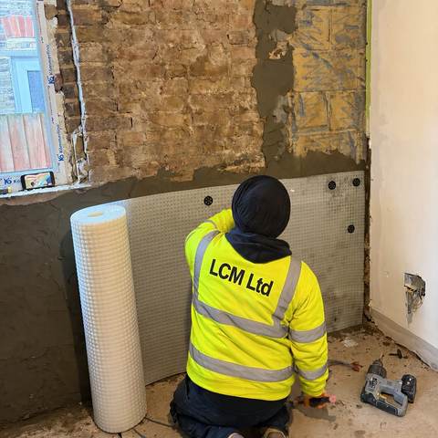 Operative fitting tanking board to a bathroom wall before tiling.