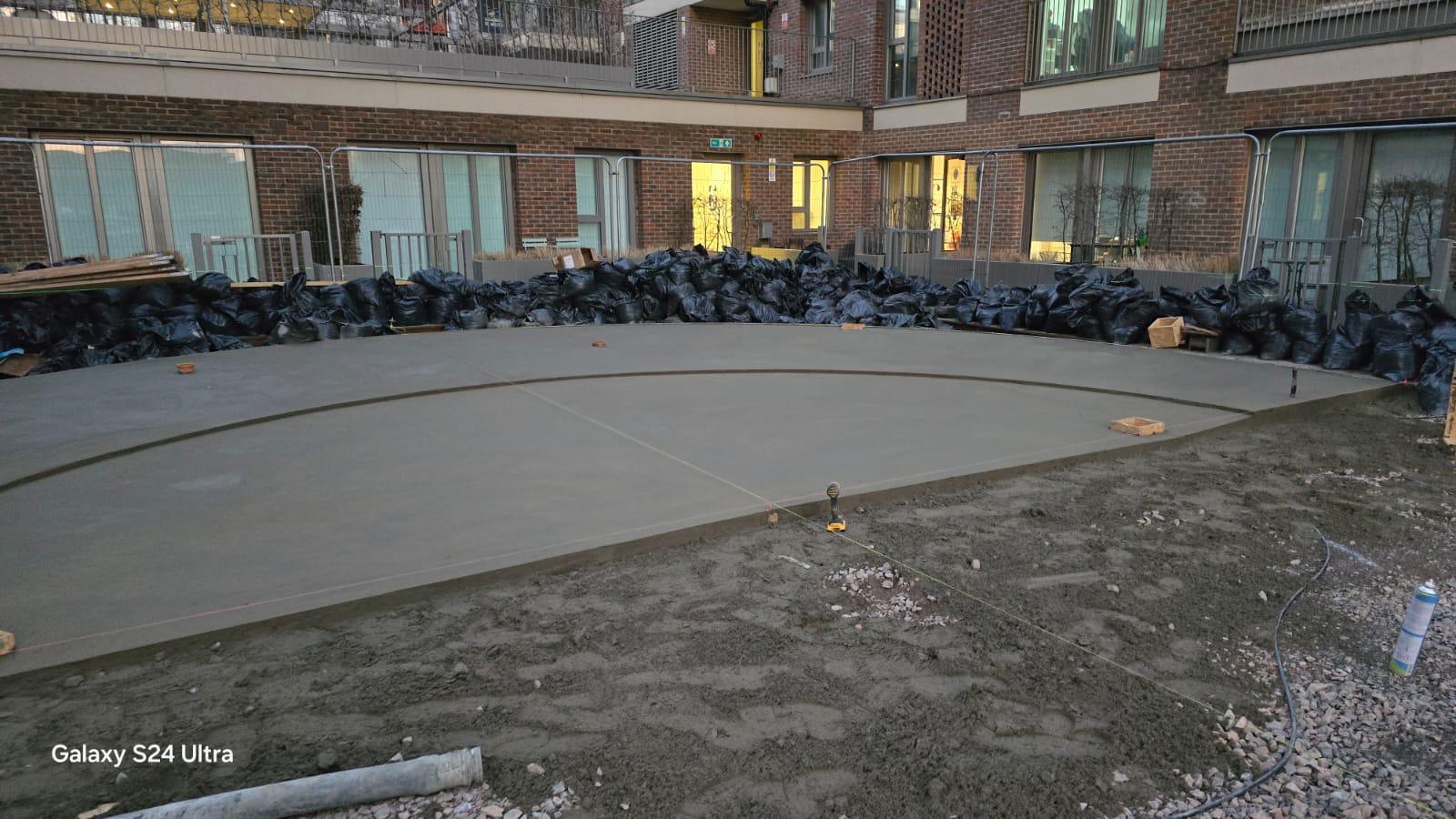 Freshly poured circular concrete slab marked out for a control joint cut in a residential courtyard.